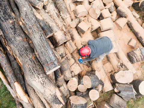 Lumberjack with a chainsaw cutting trees in the forest. Preparing firewood for winter. Top down view. Aerial view from drone

