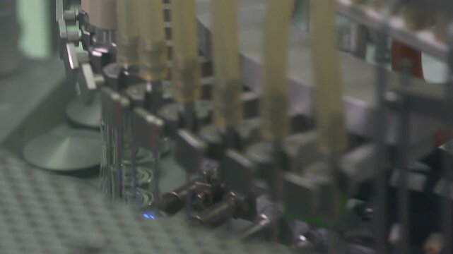 High-definition footage of an automated cleanroom assembly where glass ampoules are washed, filled with injectable medication, sterilized, and hermetically sealed. Showcases precision robotics, strict