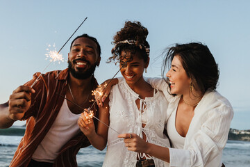 Group of friends celebrating with sparklers outdoors near the beach