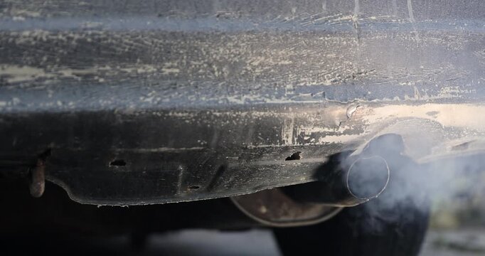 gray harmful smoke from the muffler of an old car with an inoperable or not installed filter for cleaning exhaust gases, an old pipe in the car for releasing exhaust gases from the car engine