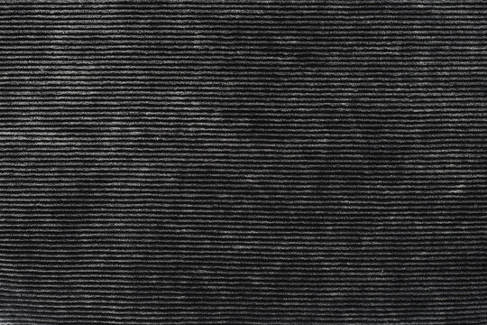 A close-up texture of black corduroy fabric with visible soft ridges