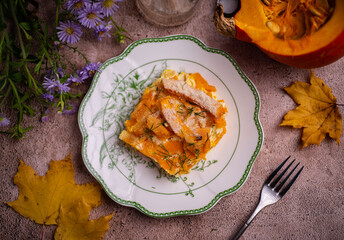 A hearty dinner: Pieces of baked pumpkin on a beautiful white plate. Pumpkin baked in cream for lunch. Top view. Close-up.