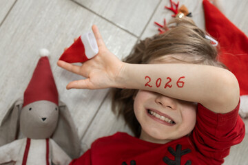 The numbers 2026 written on a child's hand covering his eyes. A happy child's face. A boy awaits a...