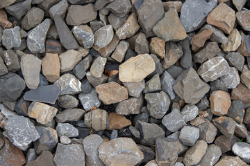 Varied assortment of natural stones and gravel in earthy tones, showcasing unique textures and shapes, perfect for landscaping, construction, or decorative purposes