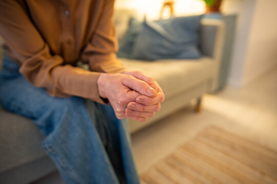 Worried female hands clasped in closed vulnerable posture on mental health consultation. Unrecognizable woman wait on sofa, anxiety therapy, stress recovery, mental health counseling, emotional stress