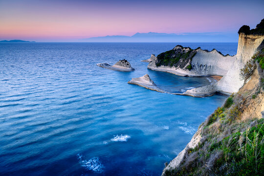 Picturesque view of Cape Drastis rock formations on island Corfu at dusk, Ionian Sea. Greek coastal scenery with rocks. Popular tourist attraction on Ionian island.