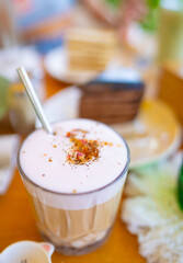 Rose latte coffee with frothy milk and flower petals in glass