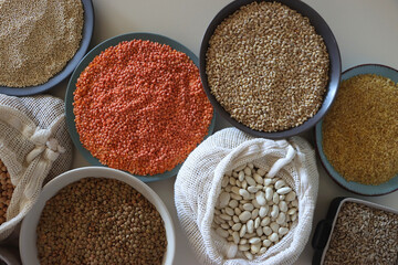 Bowls and bags full of various healthy grains and legumes. Top view.