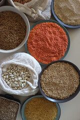 Bowls and bags full of various healthy grains and legumes. Top view.