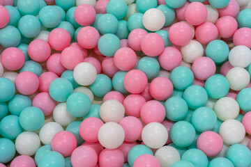 Beautiful pile of pastel-colored balls filling an indoor playground, creating a colorful texture and joyful surface.