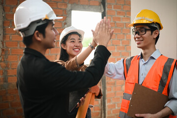 Construction team and business partners sharing high-five gesture for achievement and teamwork...