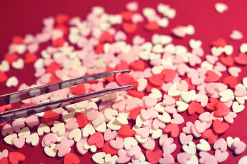 ピンセットで摘まんだハート型のトッピングシュガー　おしゃれでかわいい背景装飾　気持ち　製菓材料