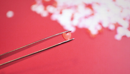 ピンセットで摘まんだハート型のトッピングシュガー　おしゃれでかわいい背景装飾　気持ち　製菓材料