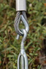 Closeup of metal fasteners and steel wire rope on natural background blur.
