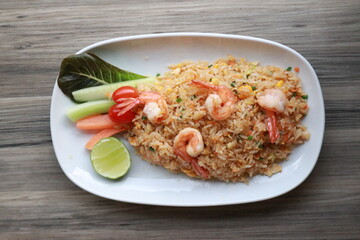 Delicious shrimp fried rice beautifully presented on a plate, garnished with fresh vegetables and a lime wedge