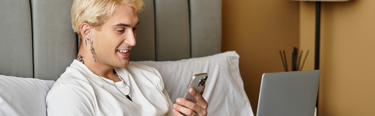 Young man enjoys relaxed moment in his modern apartment while using his smartphone and laptop