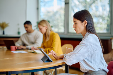 Fototapeta premium Diverse business colleagues are collaborating and working on technology devices during a meeting in a contemporary office setting