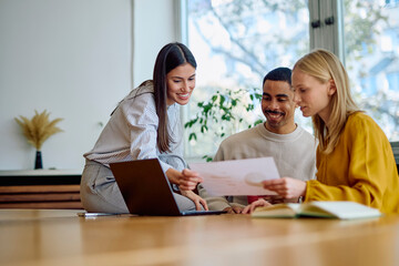 Diverse business colleagues analyzing documents and discussing project strategy, demonstrating teamwork and professional collaboration in a modern office