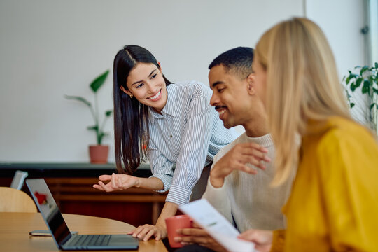 Diverse business team of coworkers meeting, discussing new project ideas, and working together on a laptop in modern office