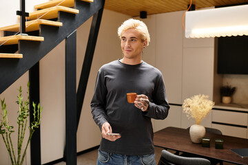 Young man enjoys a cup of coffee while relaxing in a stylish apartment interior