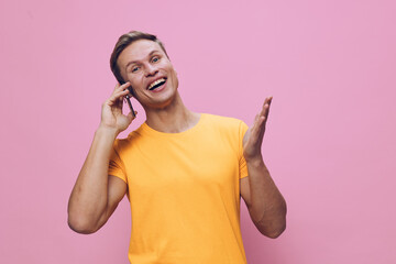 Smiling woman wearing bright yellow t-shirt talking on mobile phone and expressing happiness...