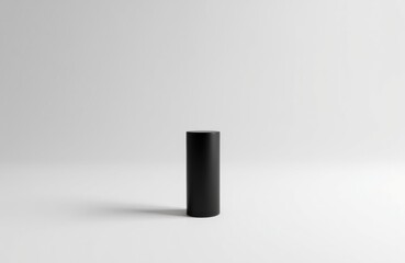 Minimalist black cylindrical object standing on a plain white surface with a neutral background