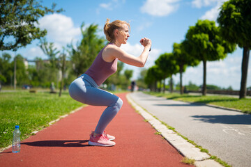 Woman performing squats on outdoor running track