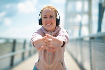 Smiling woman stretching outdoors wearing headphones
