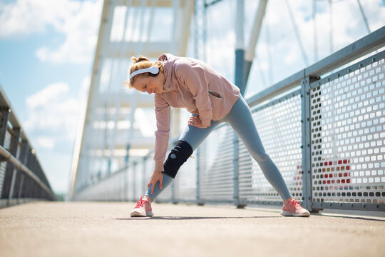 Woman with knee brace stretching on bridge