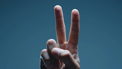 Close-up of a hand making a delicate gesture with the index and middle fingers raised, conveying precision, focus, and communication in a professional or artistic setting, against a solid dark