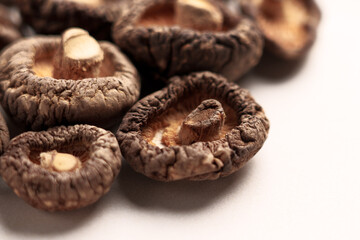 Dried shriveled edible shiitake mushrooms on beige ceramic plate close up