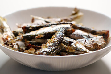 Traditional roasted sardines in white dish on home kitchen table close-up