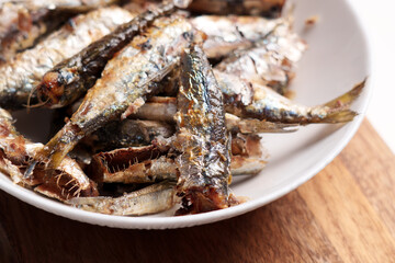 Baked sardines in a white ceramic bowl on the kitchen table