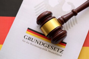 The constitution basic law book of Germany and judge hammer lies on Gremany flag background close up