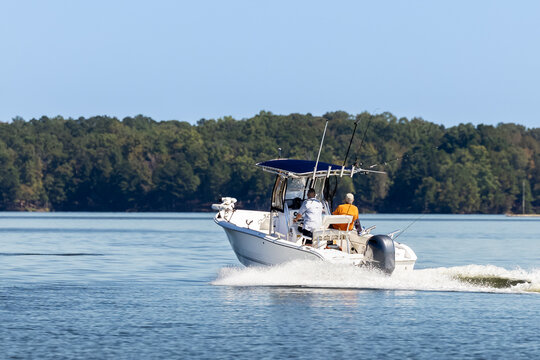 Fishermen on center console fishing boat enjoy summer day on the lake. Power boat cruising on freshwater lake.