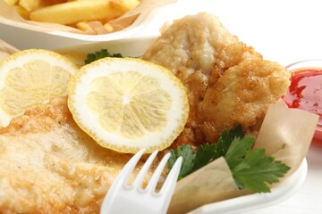 British Traditional Fish and chips with lemon and parsley served on table, closeup