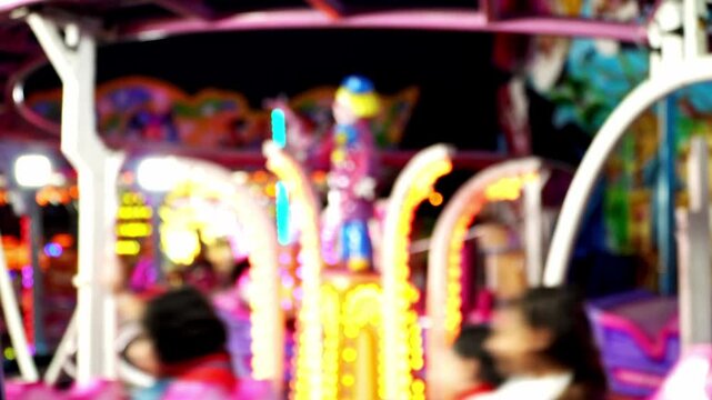 Blurred rollercoaster with colourful lighting at a night fairground, showcasing children's Christmas joy