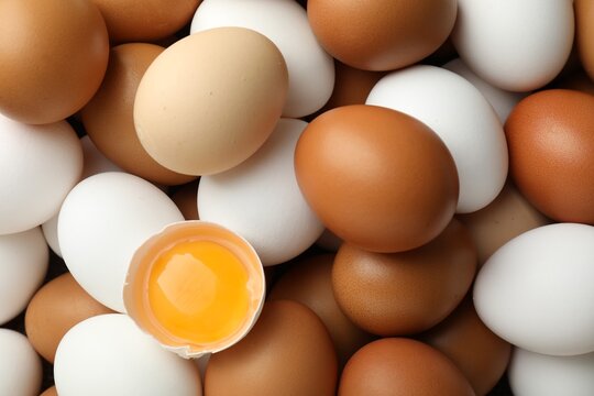 Many whole raw chicken eggs and broken one, closeup