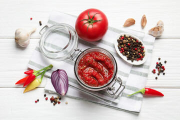 Tasty salsa sauce in jar and ingredients on white wooden table, flat lay