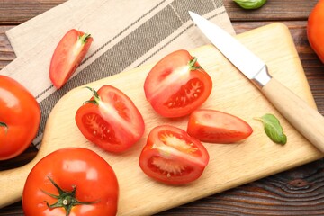 Fresh ripe tomatoes, basil and knife on wooden table, flat lay