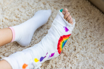 Child resting with colorful decorated leg cast on carpeted floor