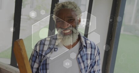 Smiling senior man holding wooden railing in modern sunroom, with hexagonal interface overlays
