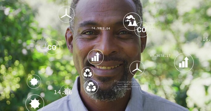 Showing mature man monitoring CO2 charts and recycling logos in sunlit garden, with turbine icons - Powered by Adobe