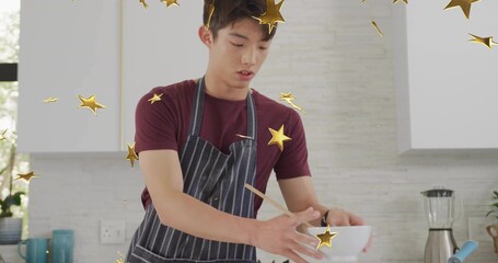 Stirring Asian teen in apron in home kitchen, with mixing bowl spoon and gold star overlays