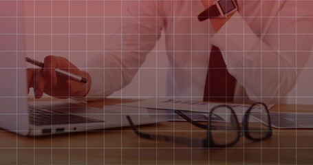 Typing businessman wearing business attire using laptop with pen at desk in office, with smartwatch