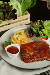 A mouthwatering dish featuring barbecued ribs, fries, and salad