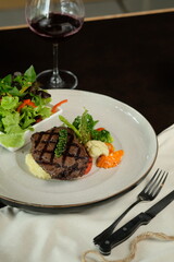 A gourmet meal featuring a perfectly grilled steak, accompanied by fresh salad and a glass of red wine. It is a delicious culinary delight