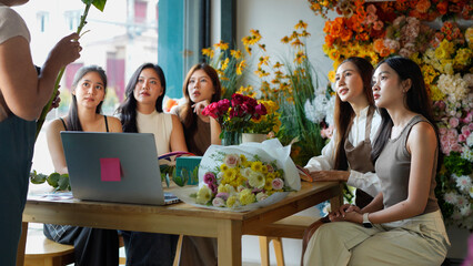 Diverse group of young people arranging flowers in florists workshop while attending class on floral art