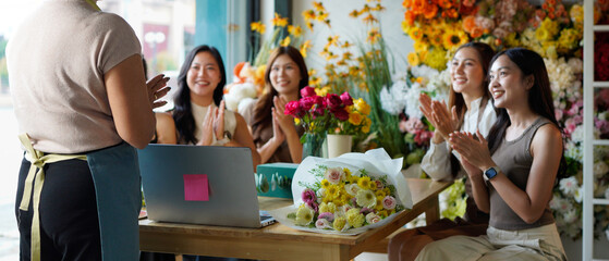 Diverse group of young people arranging flowers in florists workshop while attending class on floral art