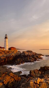 Portland Head Lighthouse Sunset in Maine New England. Pan to Sun. Wide Rocky Shore Beautiful Warm Glowing Light